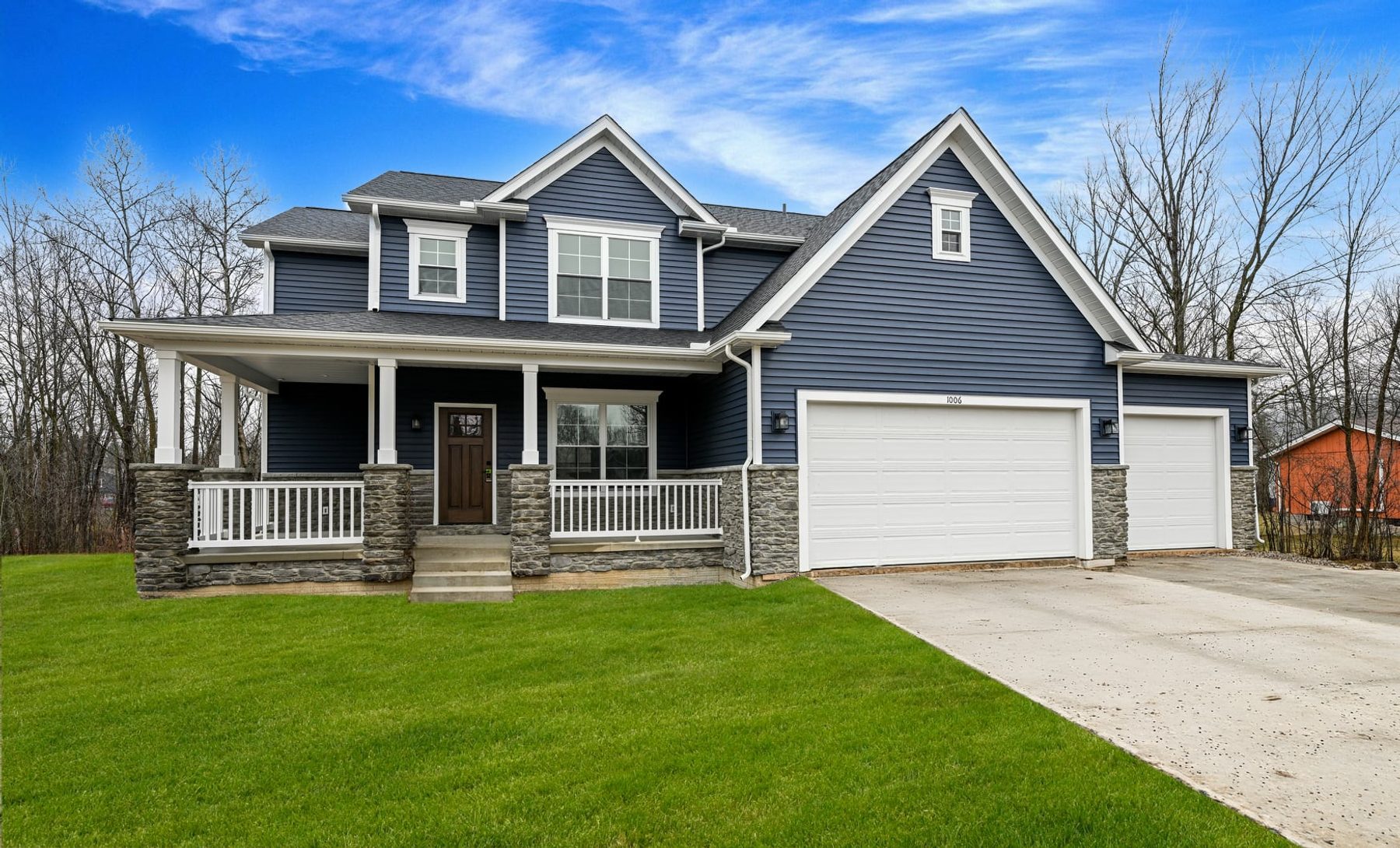 Two-story home with blue siding, stone, and a covered front porch